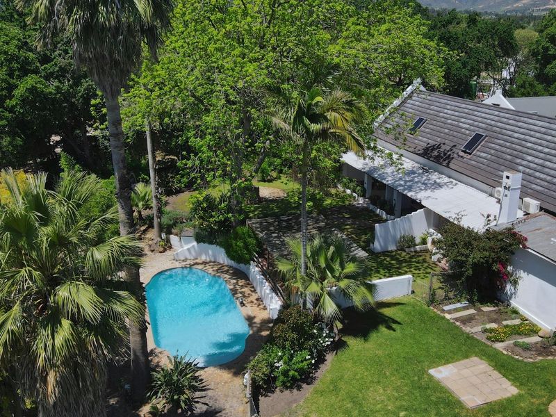 Aerial view of a small holding property featuring a swimming pool, mature garden, and a main dwelling with a tiled roof and covered patio.