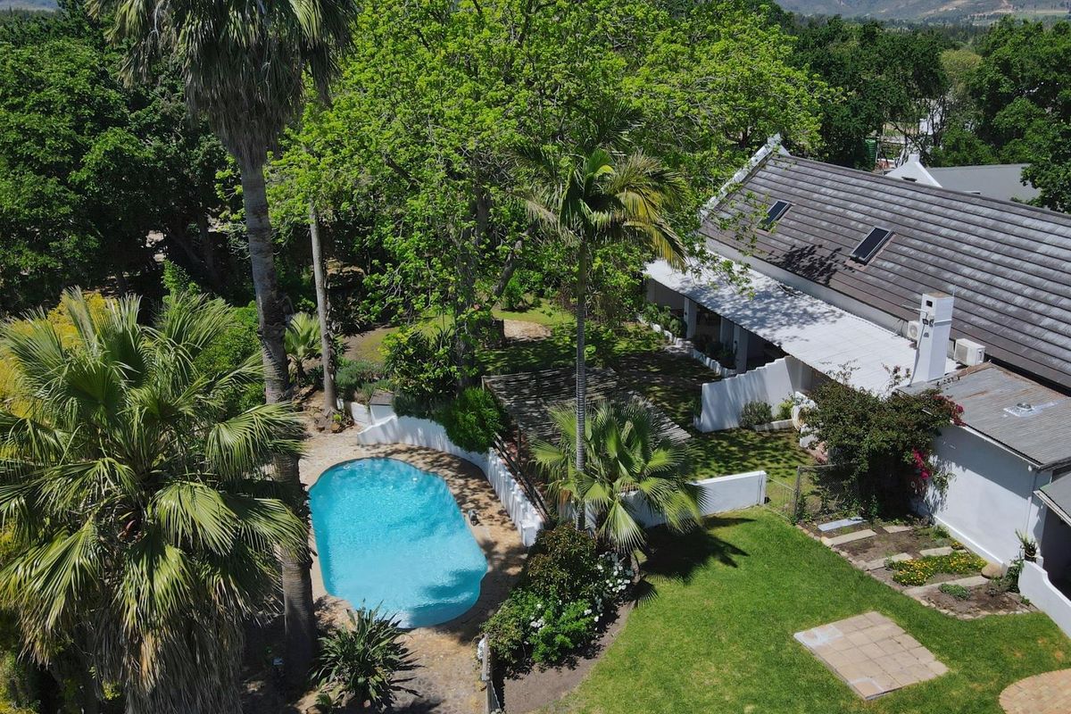 Aerial view of a small holding property featuring a swimming pool, mature garden, and a main dwelling with a tiled roof and covered patio.
