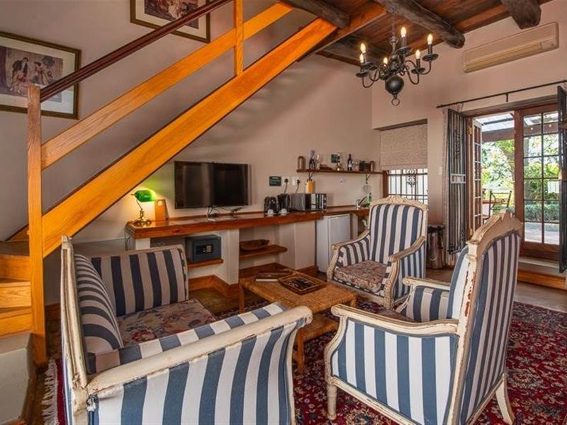 Cozy living area featuring exposed timber ceiling beams, a wooden staircase, built-in desk space, and direct access to the outdoor patio through french doors.