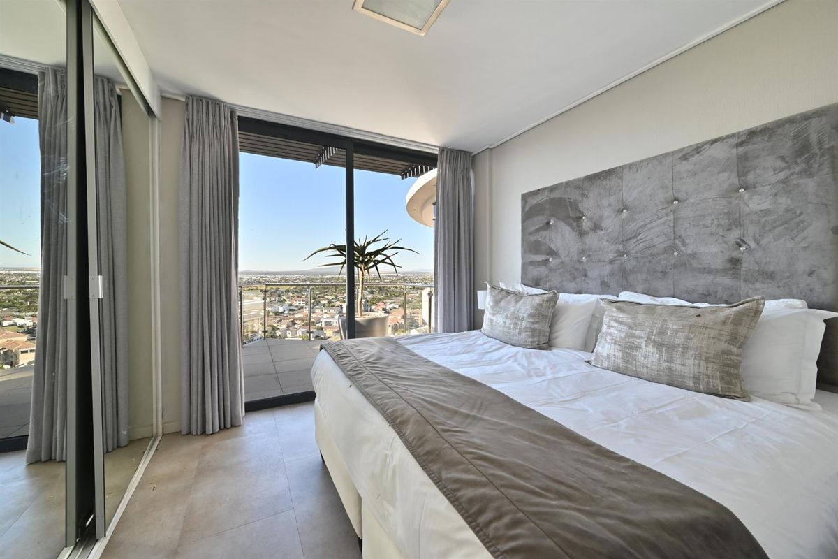 Spacious bedroom featuring large sliding glass doors that open onto a private balcony with expansive panoramic views.