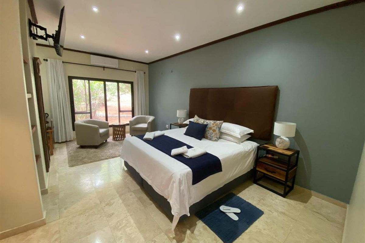 Spacious bedroom featuring tiled flooring, recessed ceiling lighting, and a wall-mounted air conditioning unit with direct access to an outdoor area.