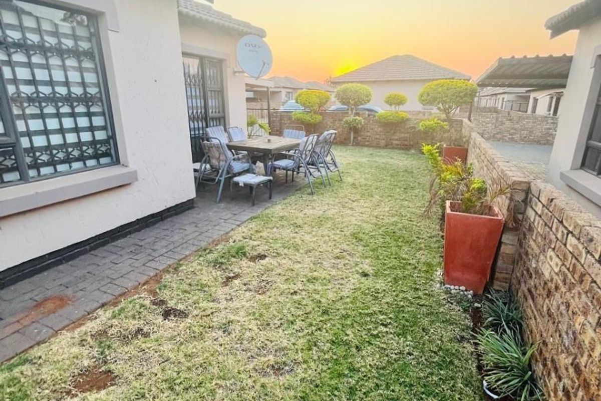 A private rear garden featuring a paved patio area, brick boundary walls, and a small lawn, ideal for outdoor relaxation.