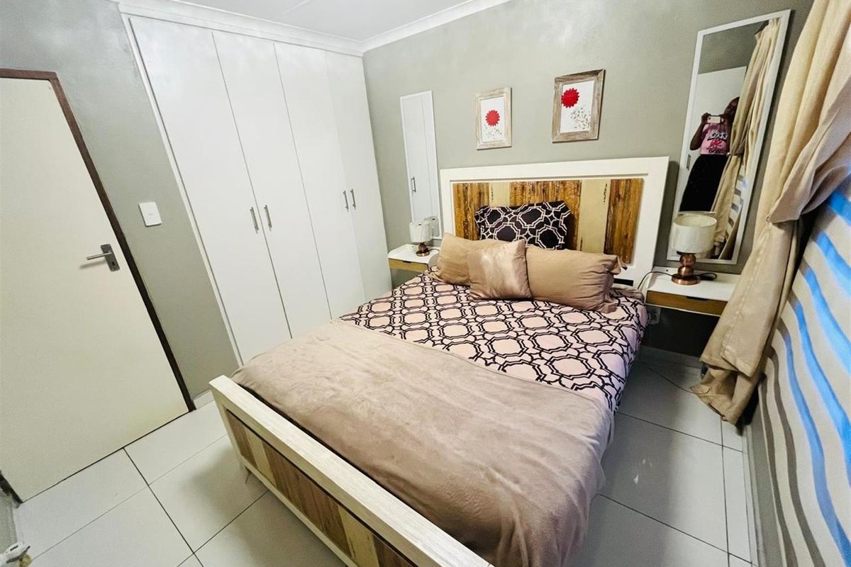 A well-maintained bedroom featuring built-in white cabinetry, tiled flooring, and neutral wall finishes, providing a clean and functional living space.