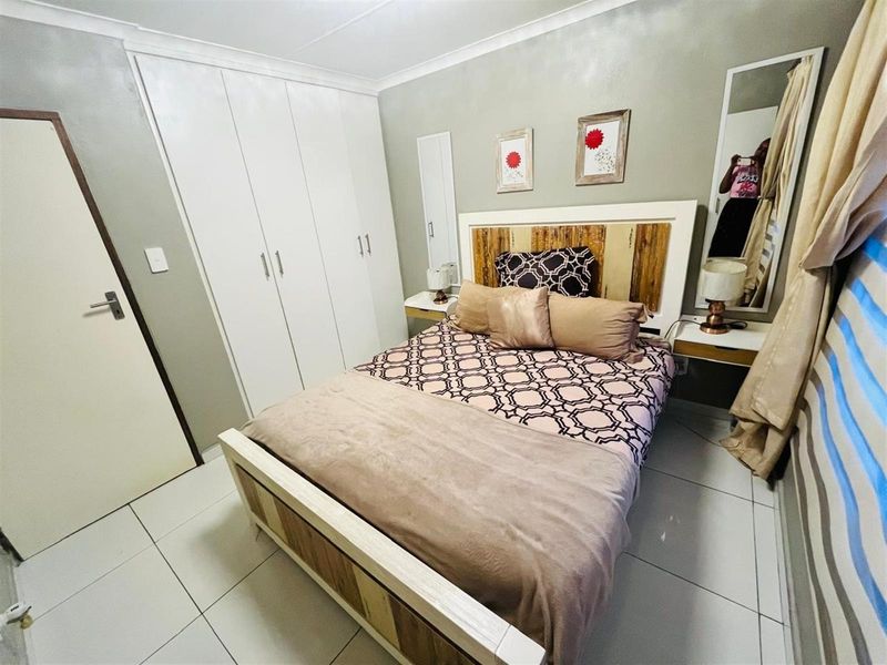 A well-maintained bedroom featuring built-in white cabinetry, tiled flooring, and neutral wall finishes, providing a clean and functional living space.