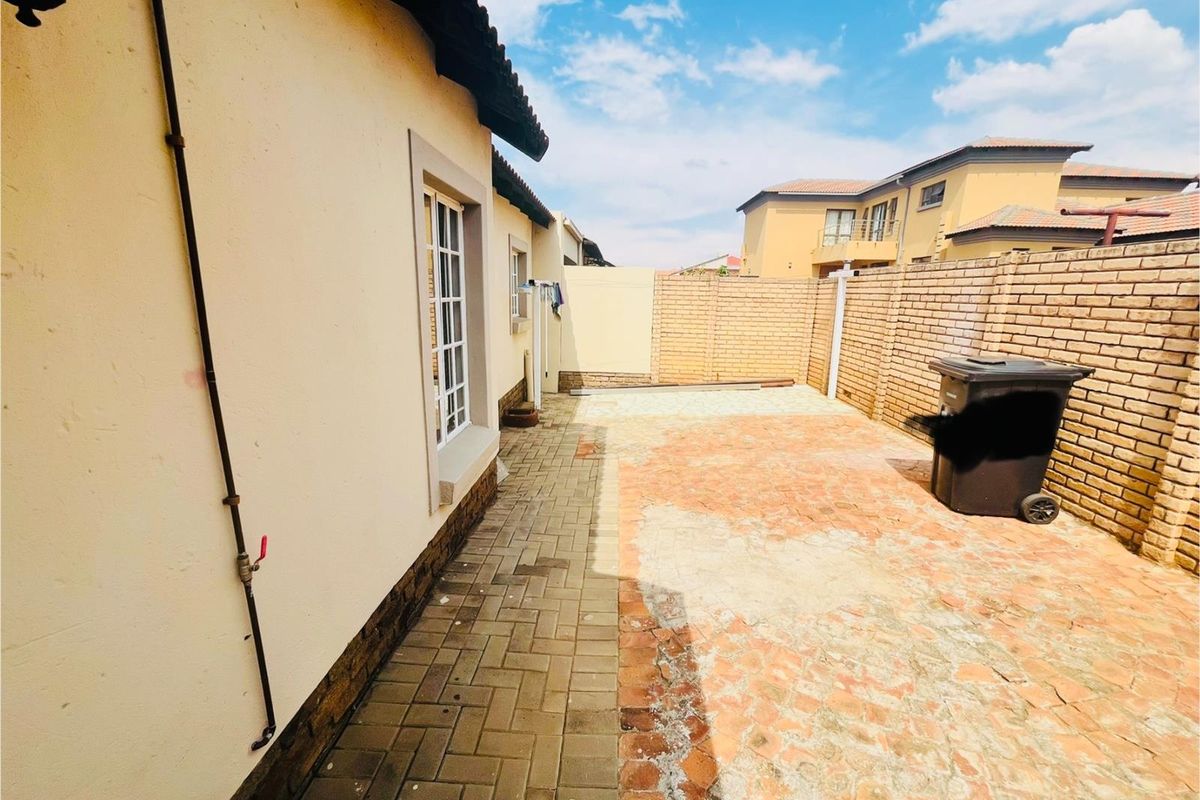 A private rear courtyard featuring paved flooring and perimeter brick boundary walls, offering a functional outdoor space for the townhouse.