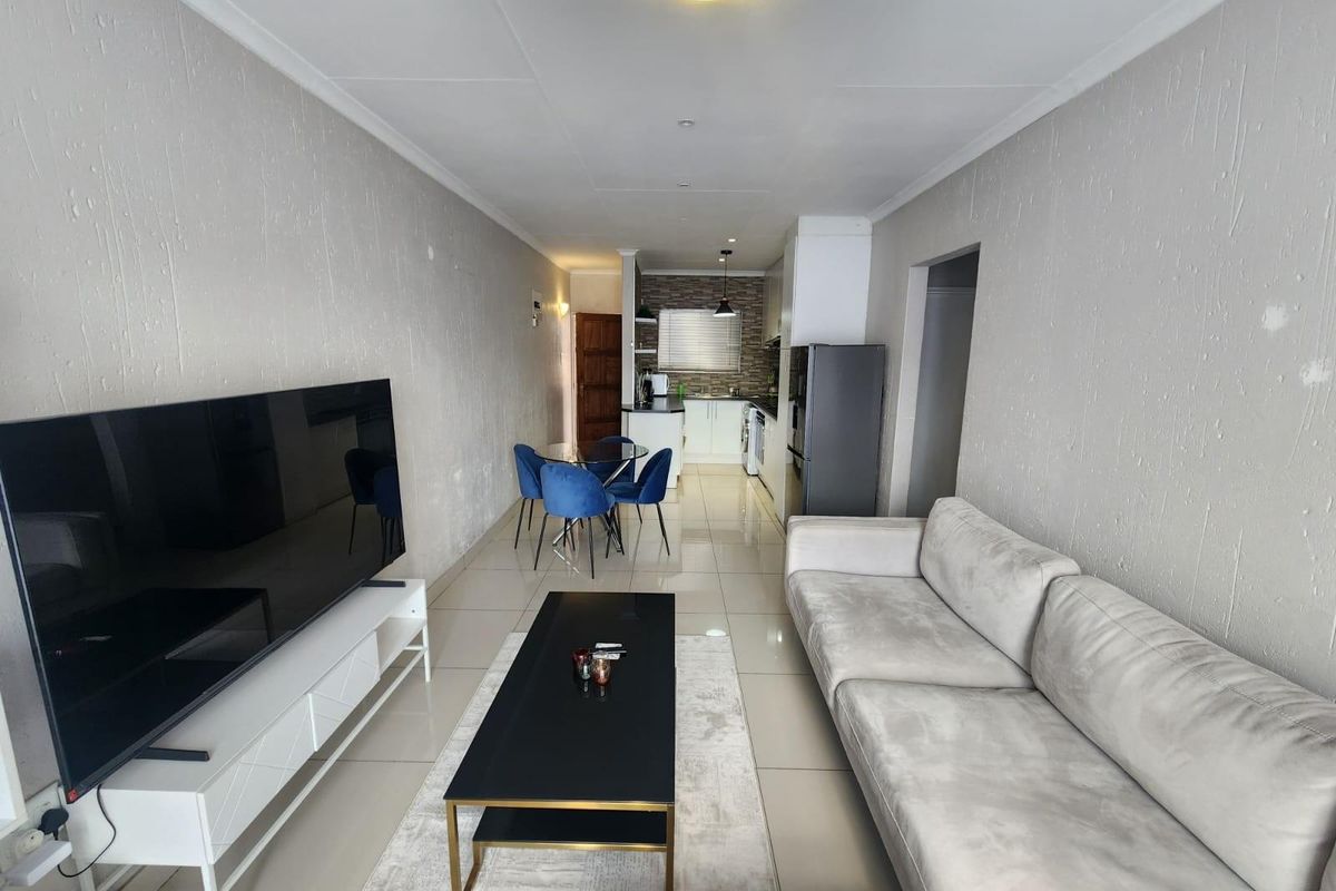 Open-plan living and dining area featuring tiled floors, coved ceilings, and a functional kitchen with built-in cabinetry and countertops.