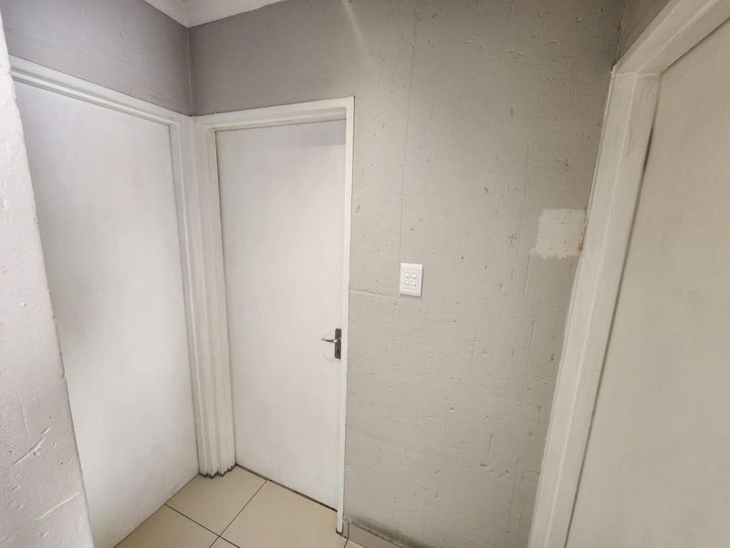 A functional hallway area featuring tiled flooring and multiple internal doors, currently requiring cosmetic attention to the wall finishes.