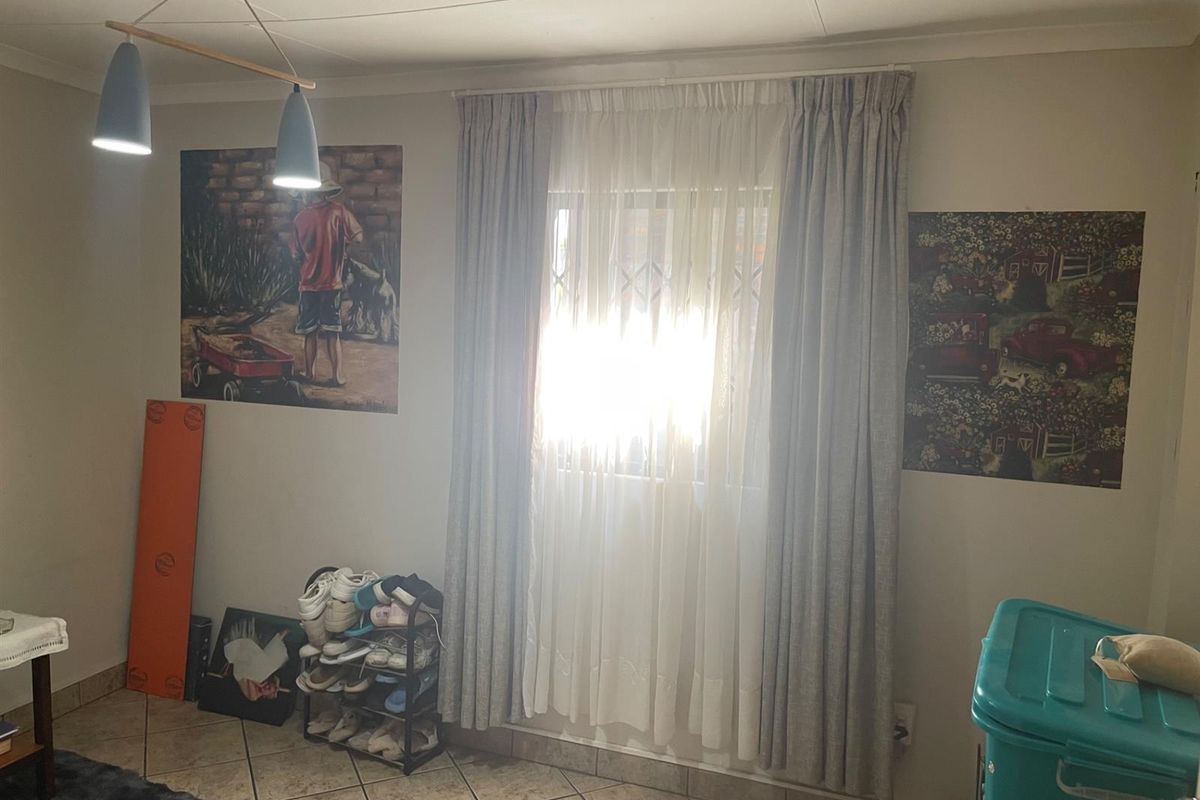 A bedroom featuring tiled flooring, a central window with curtain treatments, and overhead pendant lighting.