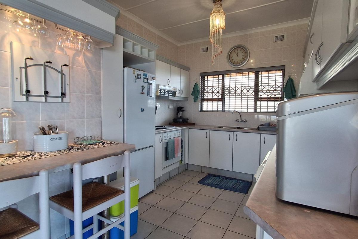 A functional kitchen featuring white cabinetry, tiled flooring, a built-in stove, and a breakfast counter area with overhead glass storage.
