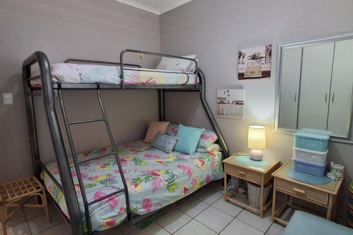 A functional bedroom featuring tiled flooring and built-in wardrobe space, suitable for a child or guest room.