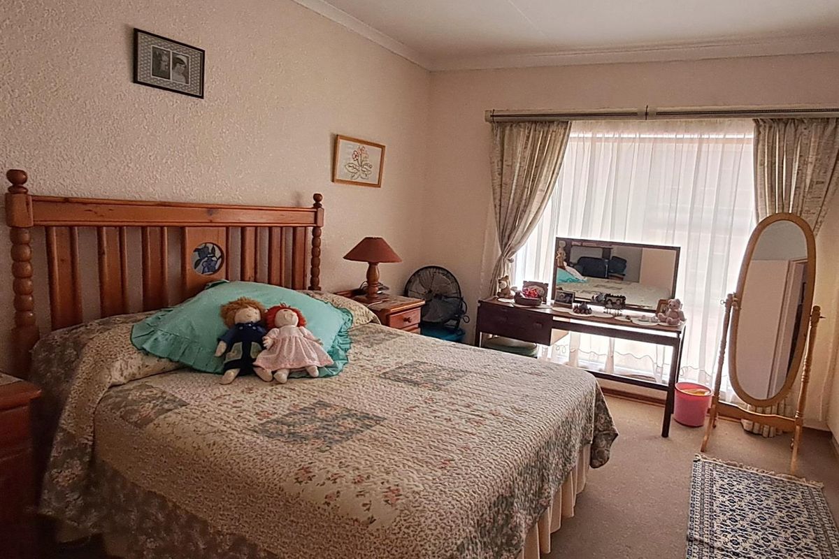 A well-maintained bedroom featuring neutral wall finishes, carpeted flooring, and large windows with curtain tracks, providing a comfortable and functional living space.