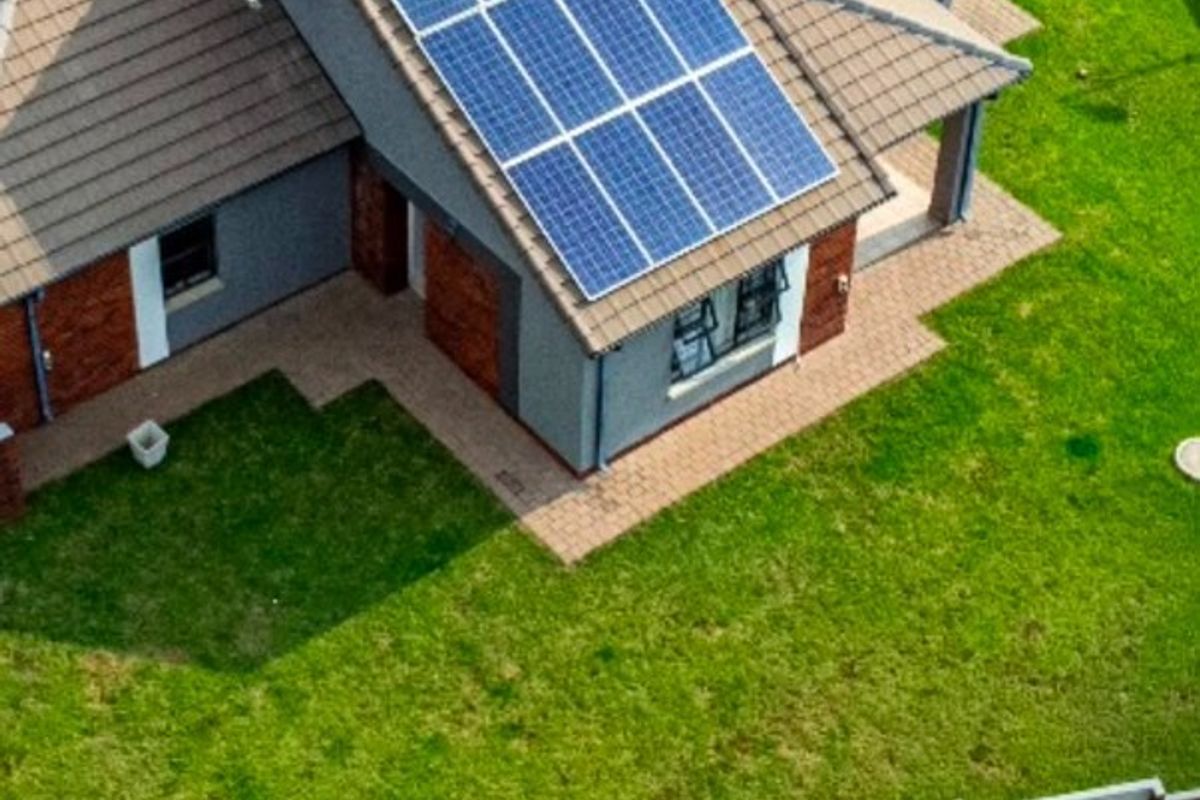 Aerial view of a residential property featuring a tiled roof with installed solar panels, a well-maintained lawn, and brick boundary walling.