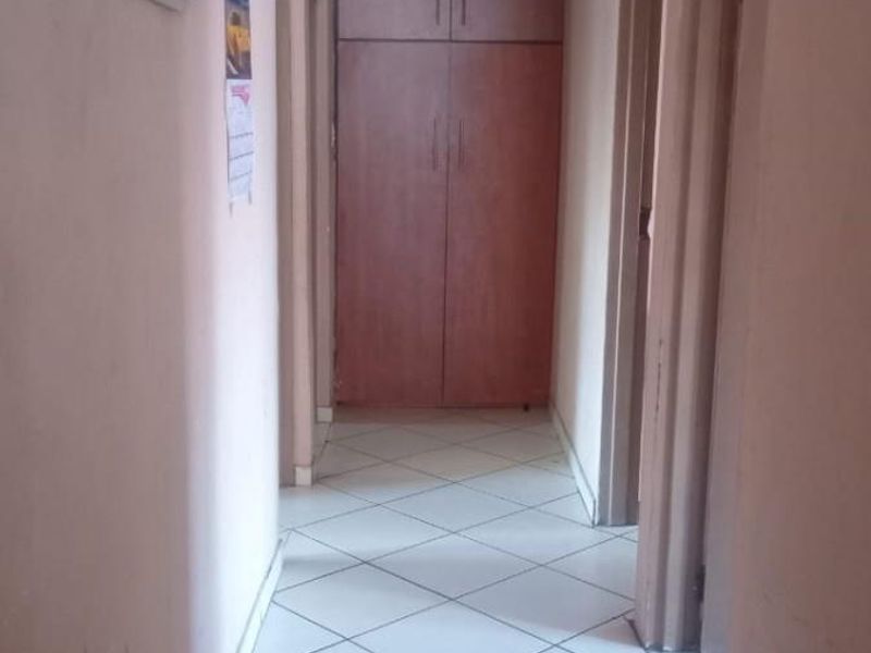 A functional hallway featuring tiled flooring, built-in storage cupboards, and ceiling paneling, providing access to multiple rooms within the home.
