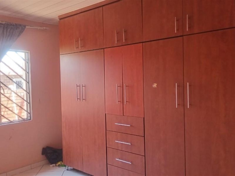 A bedroom featuring extensive built-in wooden cabinetry with integrated drawers and security bars on the window.
