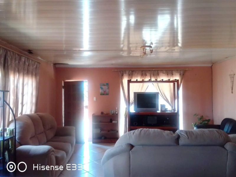 A living room featuring tiled flooring and a glossy PVC panel ceiling, requiring cosmetic updates to modernize the space.