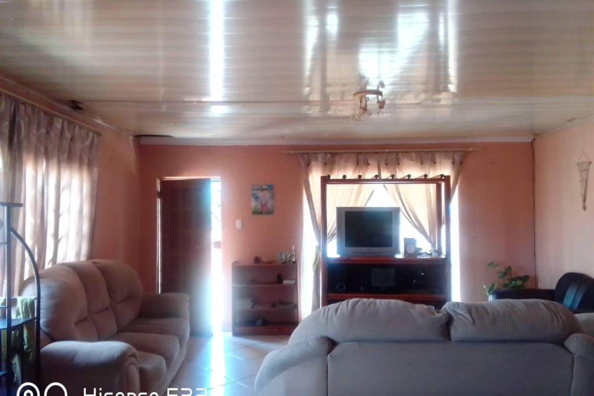 A living room featuring tiled flooring and a glossy PVC panel ceiling, requiring cosmetic updates to modernize the space.