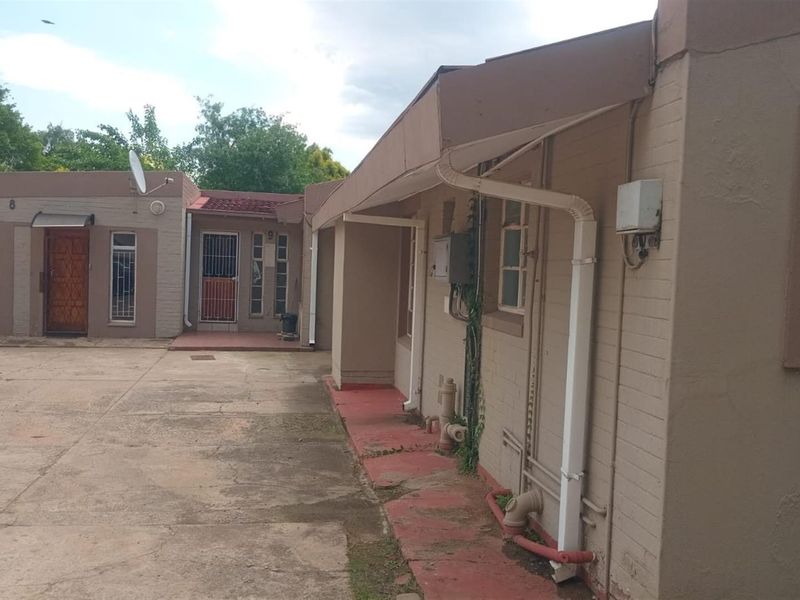 Rear exterior view of a commercial property featuring concrete paving, security-fitted windows and doors, and external utility infrastructure.