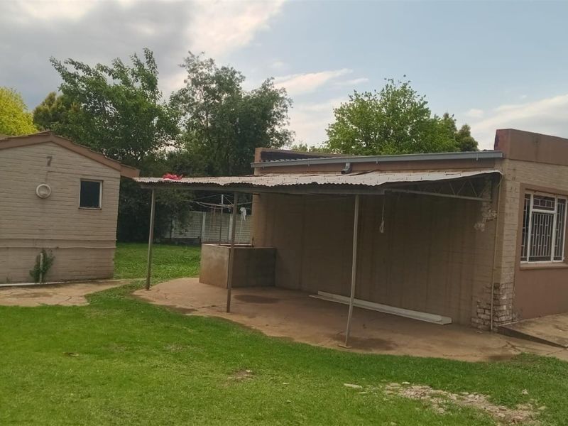 Rear view of the commercial property featuring a covered patio area, brick exterior walls, and a surrounding lawn.