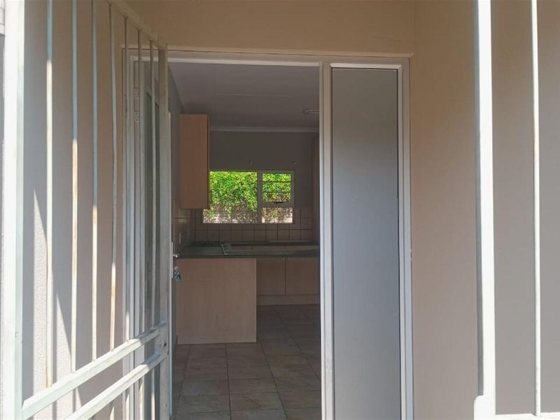 View through a security gate into a kitchen area with tiled flooring and built-in cabinetry.
