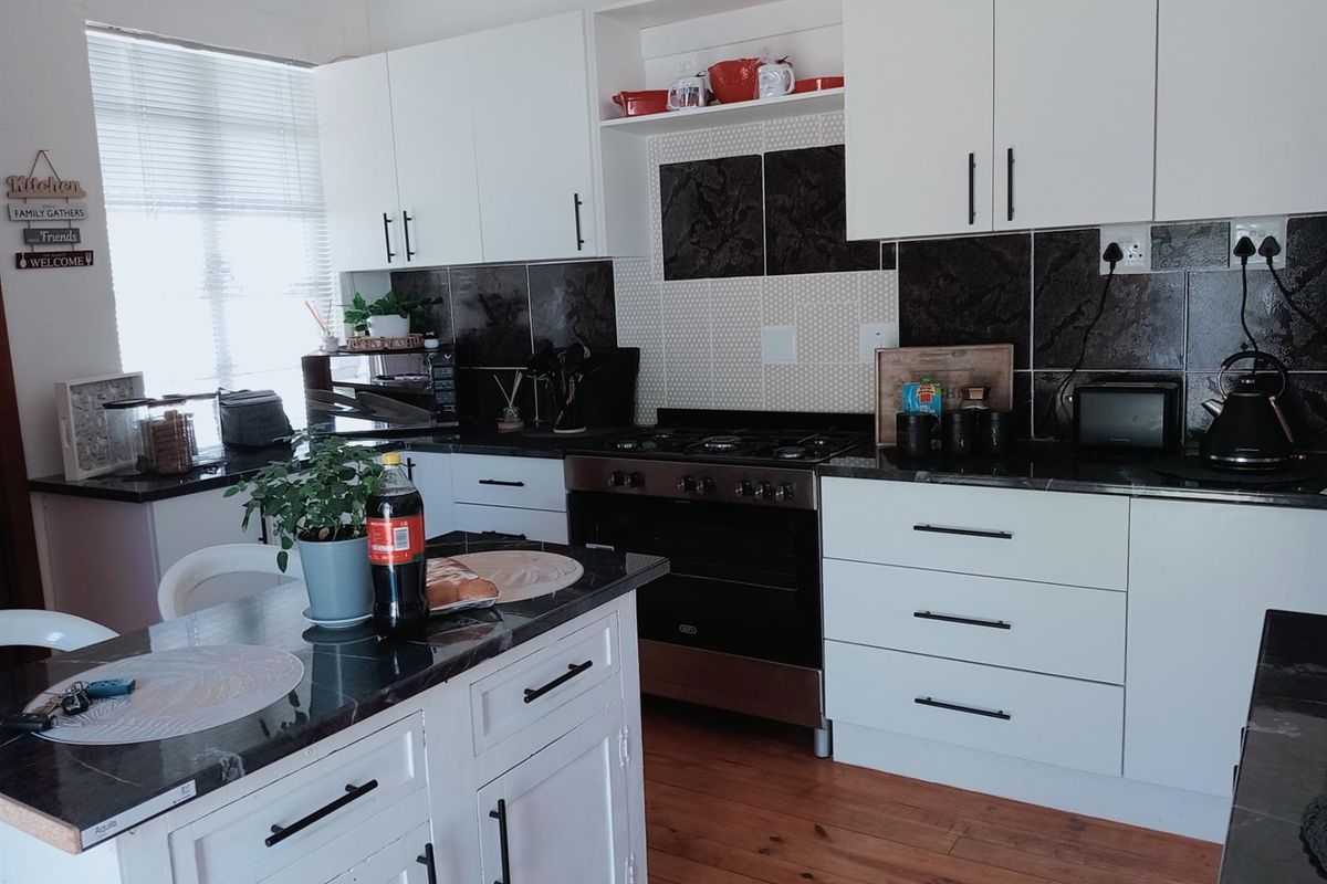 Modern kitchen featuring white cabinetry, dark stone countertops, a central island, and a built-in gas stove with a tiled backsplash.