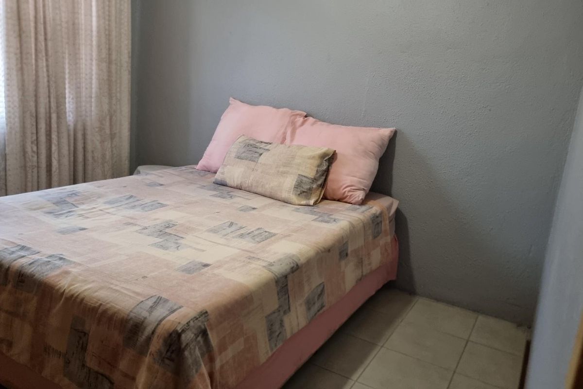 A simple bedroom featuring tiled flooring and grey painted walls.