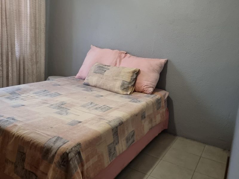 A simple bedroom featuring tiled flooring and grey painted walls.