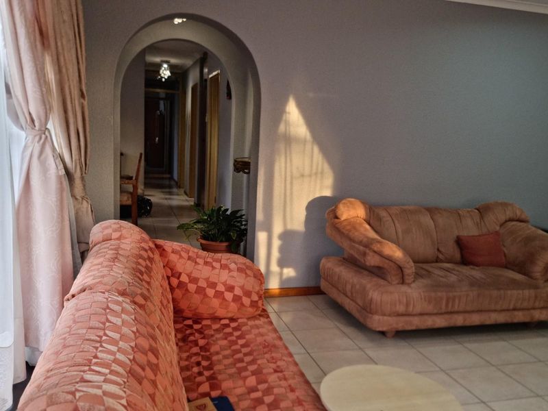 A living room featuring tiled flooring and a distinctive arched doorway leading to a hallway, providing a functional and traditional layout.