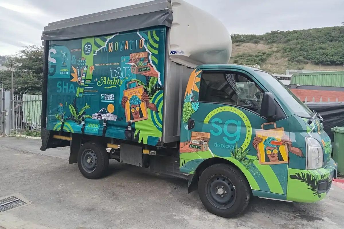 A commercial delivery truck parked on a paved surface, featuring branded graphics for a packaging and printing business.