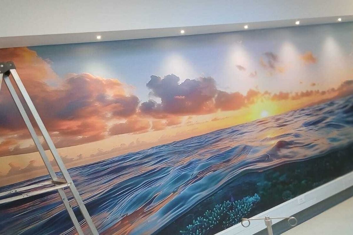 Interior space featuring a large, high-quality sunset ocean mural on the main wall, illuminated by recessed ceiling spotlights.