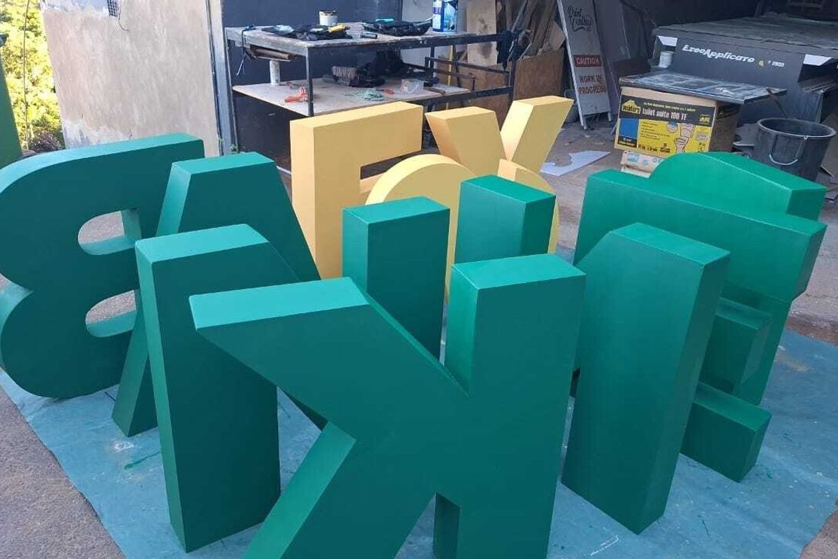 An outdoor workspace area featuring large signage letters, currently used for storage and construction-related activities.