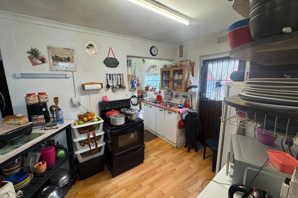A functional kitchen space featuring a freestanding stove, built-in cabinetry, and laminate flooring, offering a practical layout for daily meal preparation.