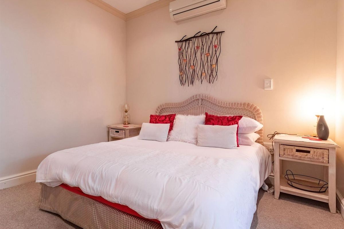 A comfortable bedroom featuring neutral carpeting, crown molding, and a wall-mounted air conditioning unit.