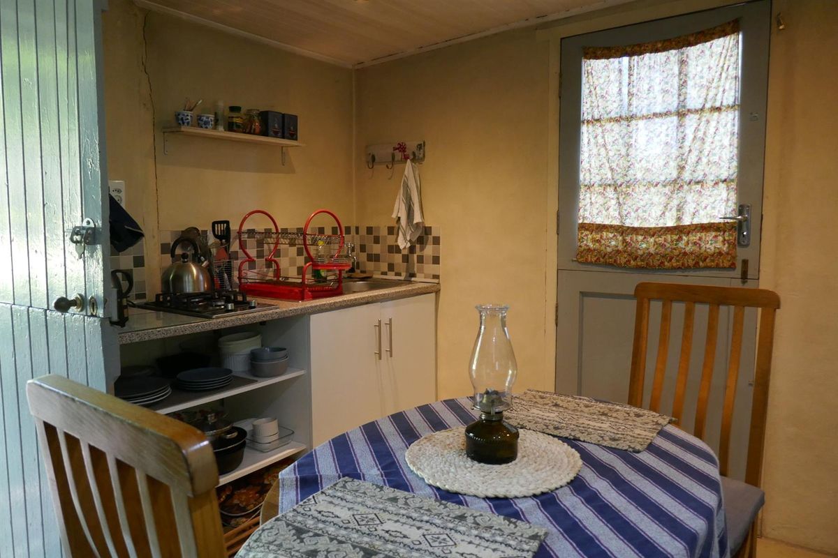 A compact kitchen area featuring basic cabinetry, a small countertop with a built-in sink, and a stable door leading to the exterior.