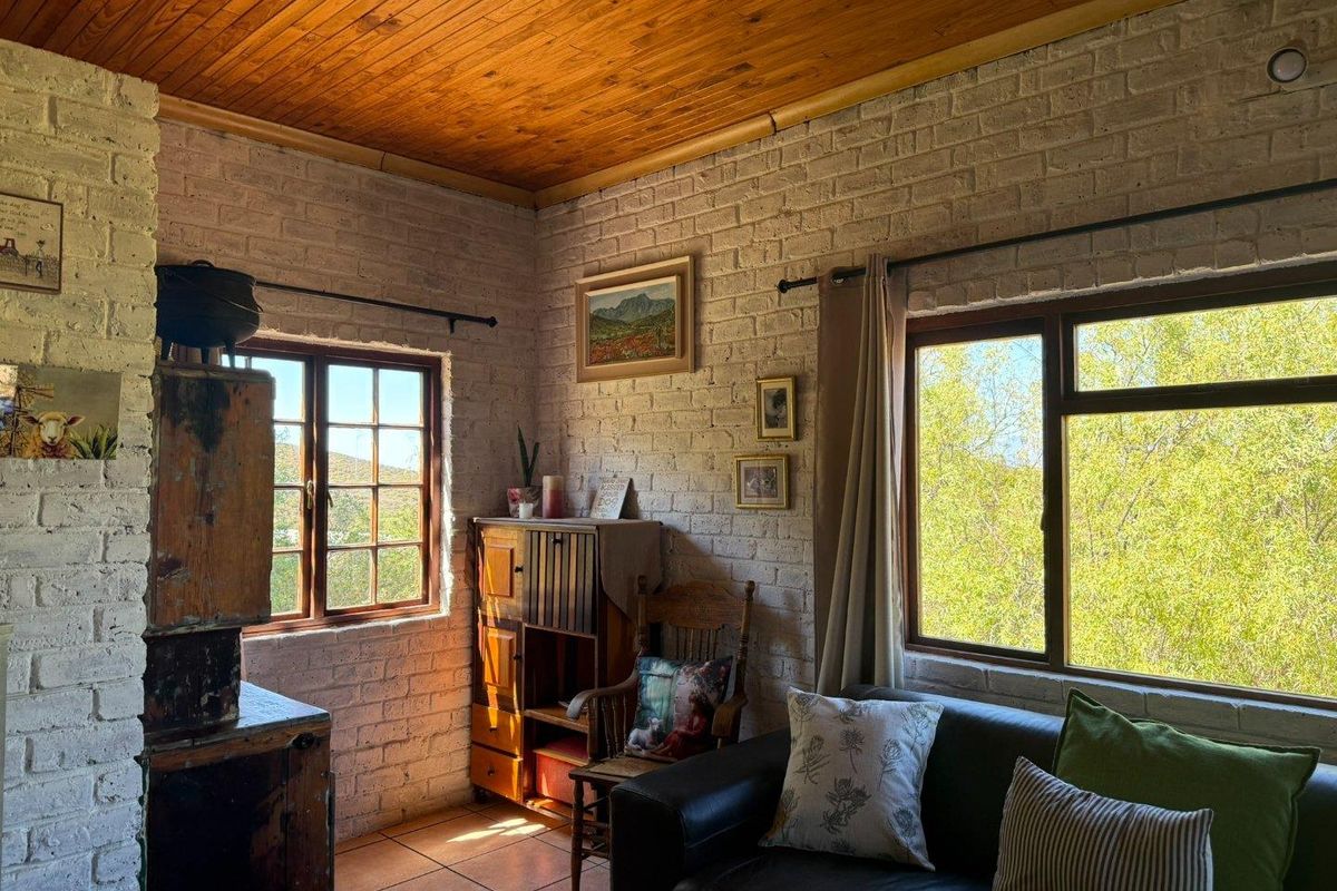 Cozy living area featuring rustic exposed brick walls, a warm timber ceiling, and large windows providing natural light and scenic views.