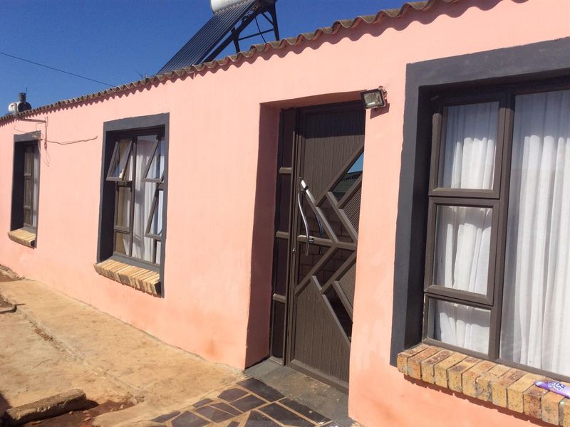 Front exterior view of the house featuring a security gate, solar water heater, and brick window sills.