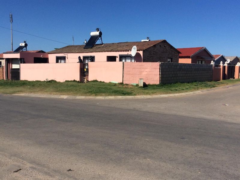 Street view of a single-story residential property featuring a perimeter wall, tiled roof, and installed solar water heating system.