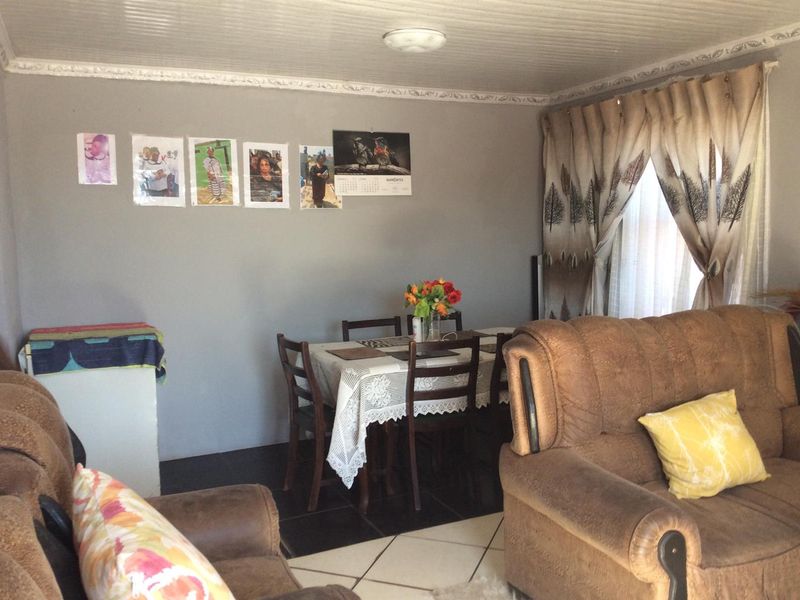 A living room area featuring tiled flooring, decorative ceiling molding, and a tongue and groove ceiling finish.