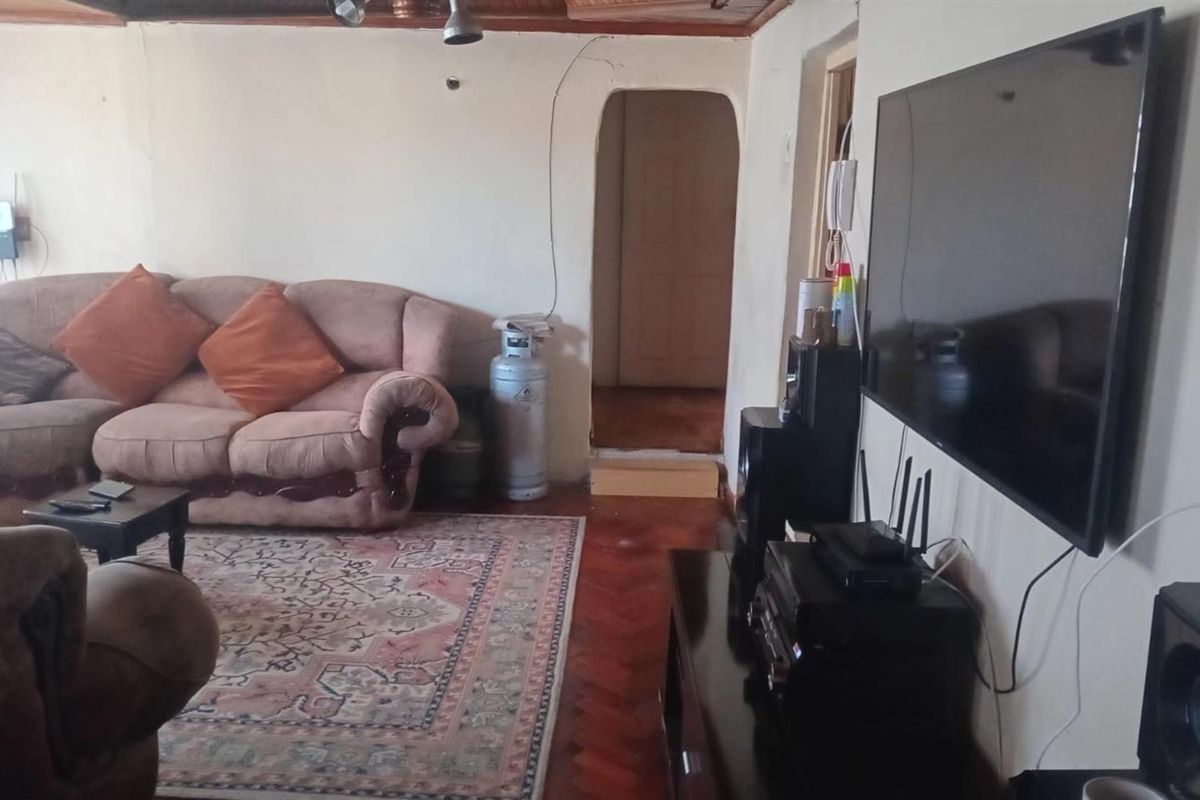 A living room featuring traditional timber flooring, an arched doorway, and wall-mounted television space.