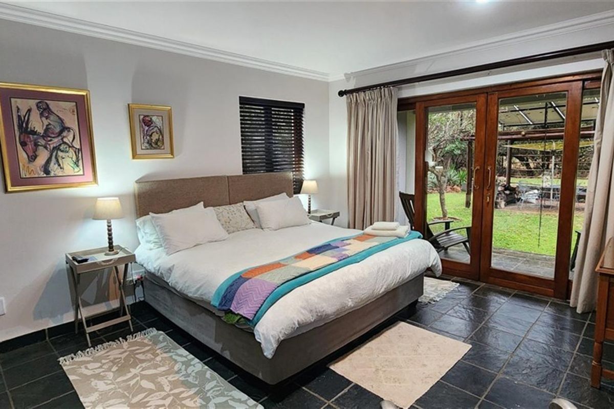 Spacious bedroom featuring dark slate flooring, crown molding, and large wooden sliding doors providing direct access to the rear garden.