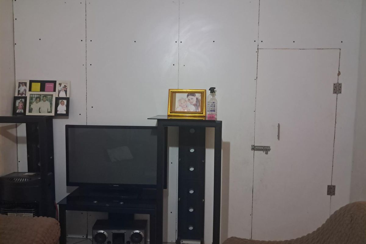 A living area featuring unfinished drywall wall panels with visible screw heads and a basic integrated door.
