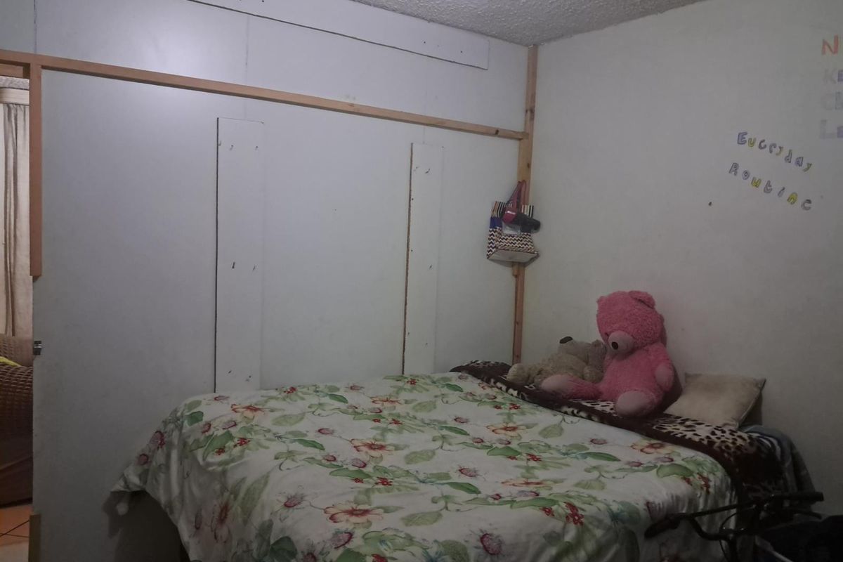 A bedroom featuring unfinished wall paneling and exposed timber framing, requiring cosmetic updates to improve the overall finish and aesthetic appeal.