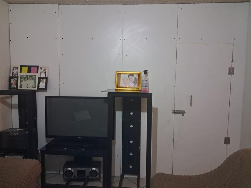 A living area featuring unfinished drywall wall panels with visible screw heads and a basic integrated door.