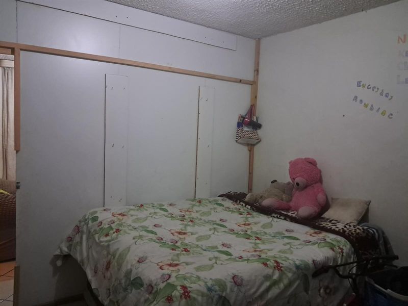 A bedroom featuring unfinished wall paneling and exposed timber framing, requiring cosmetic updates to improve the overall finish and aesthetic appeal.
