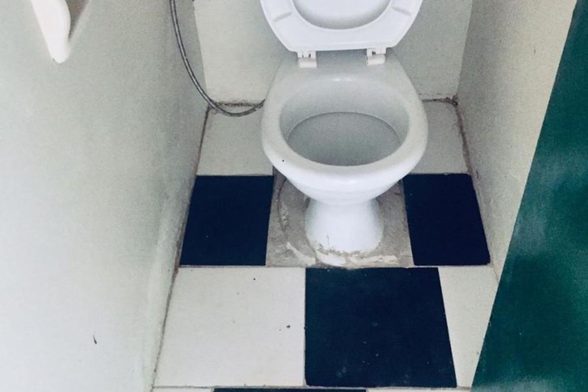 A small bathroom featuring a toilet with a checkered tile floor, requiring maintenance and cosmetic updates to improve its overall condition.