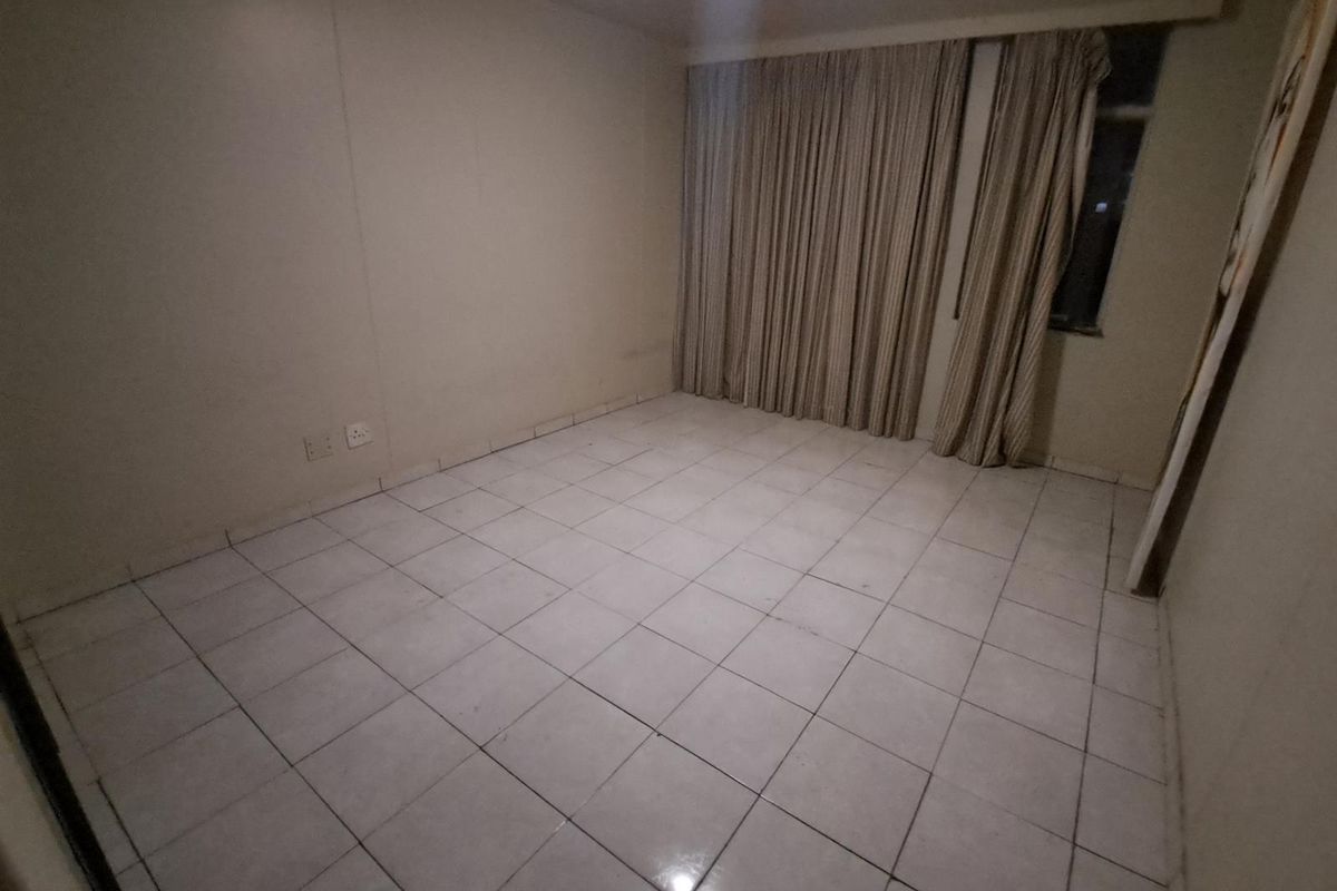 An empty bedroom featuring tiled flooring and full-length curtain tracks, providing a blank canvas for personalization.