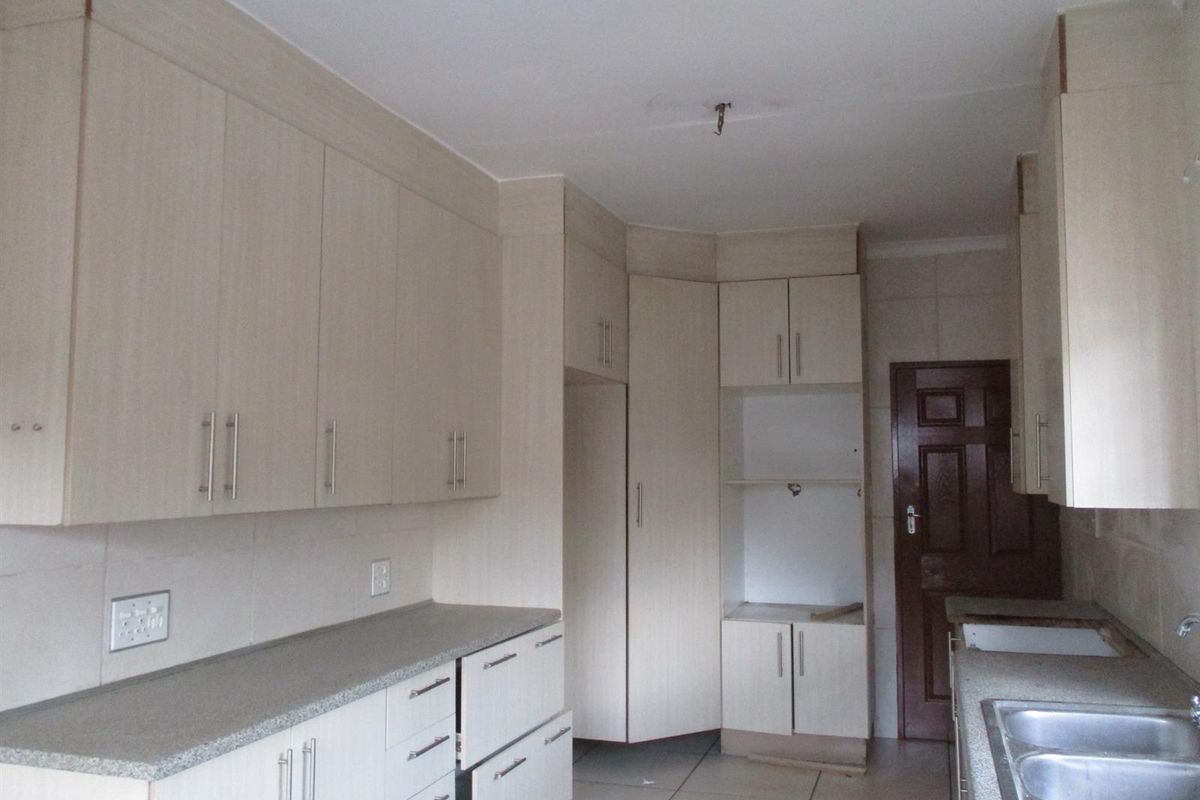 A functional kitchen space featuring light-toned built-in cabinetry, laminate countertops, and a double bowl sink, currently awaiting appliance installation.