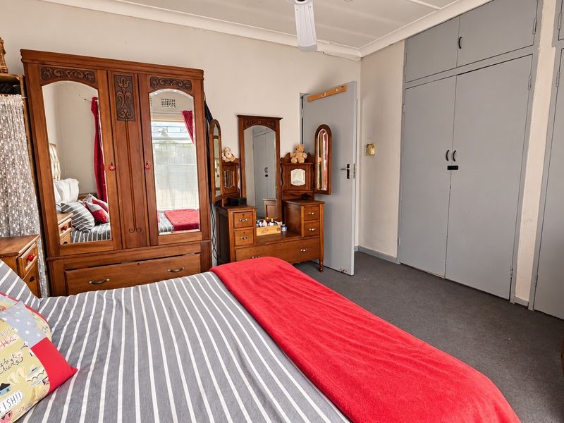 A bedroom featuring built-in cupboards and a ceiling fan, offering a functional space with neutral wall finishes.