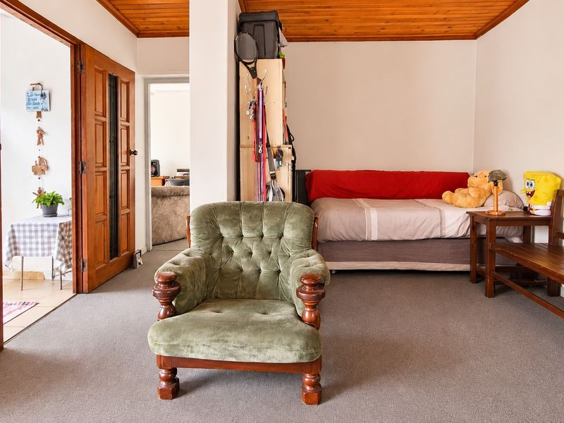 A living area featuring a timber ceiling, carpeted flooring, and wooden door access to adjacent rooms.