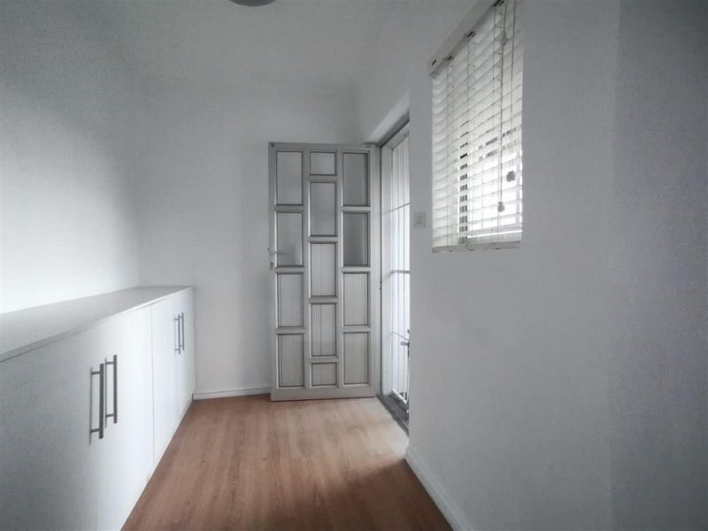 A bright entrance hallway featuring built-in cabinetry, wood-look flooring, and a decorative glass-panelled door leading to the exterior.