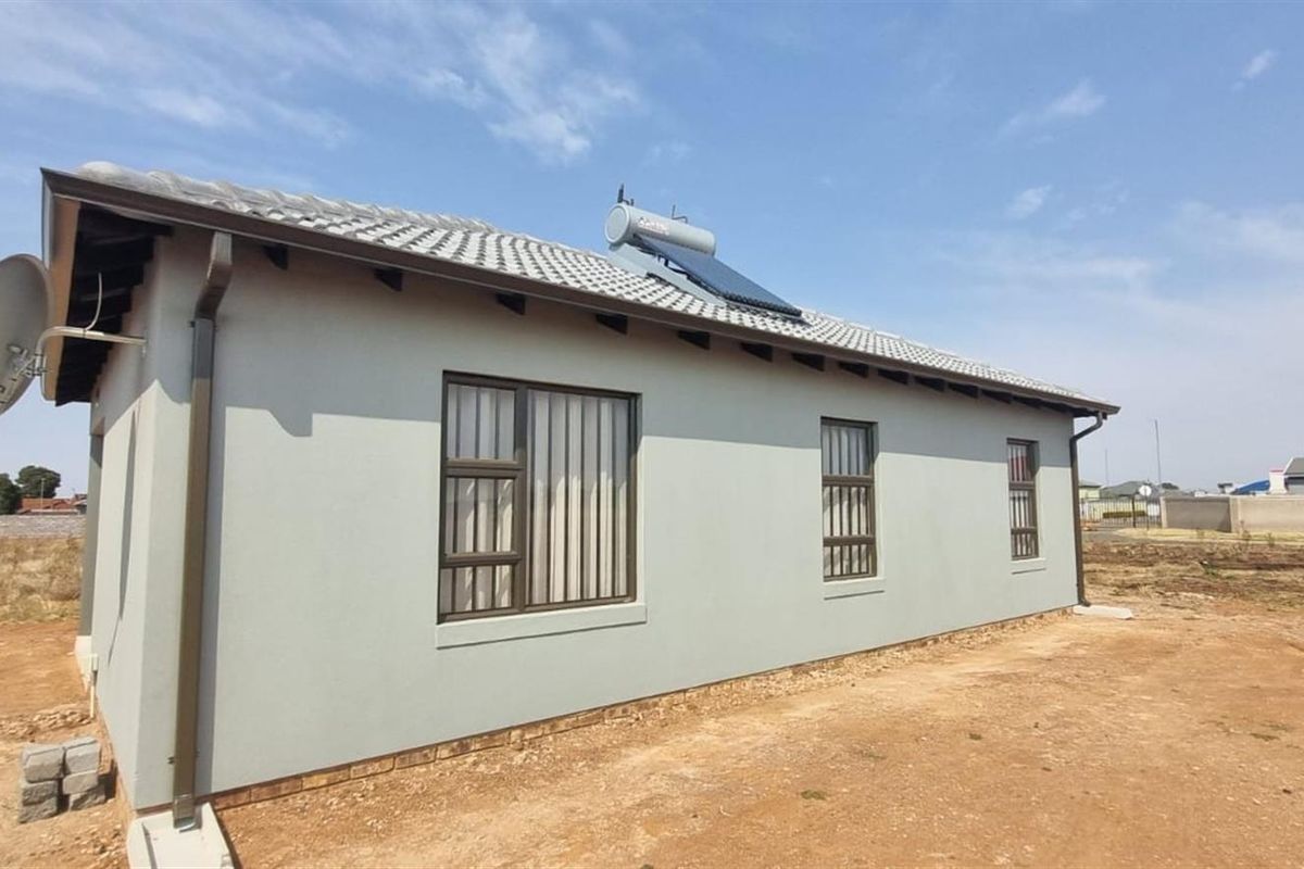 Exterior view of the house featuring a tiled roof, solar water heating system, and aluminium window frames with security bars.